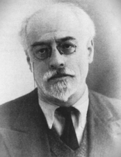 Potrait von Volin. Er trägt eine Brille mit Band und hält den Kopf leicht zur Seite geneigt. Ernster, melancholischer Blick